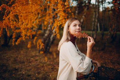 Beautiful young woman holding autumn tree in forest