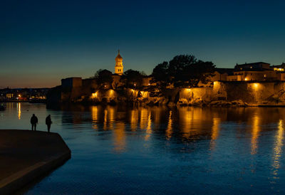 Lighthouse by river against sky at night