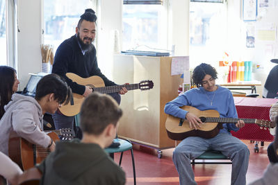 Teenagers attending guitar lesson