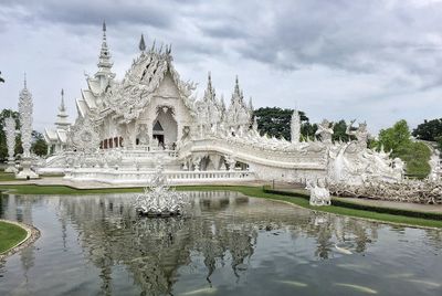 Fountain in front of temple against cloudy sky