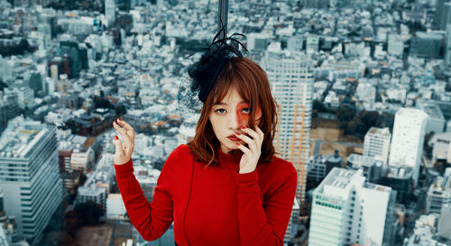 Portrait of young woman standing against cityscape in city