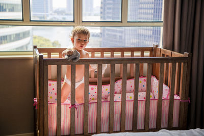 Portrait of boy standing against window