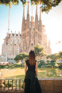 Rear view of woman standing outside temple against buildings