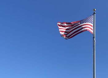 Low angle view of flags against clear blue sky