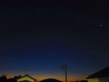 Low angle view of silhouette electricity pylon against sky at night