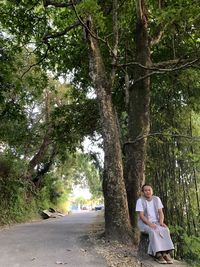 Woman standing by tree against plants