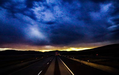 Country road against cloudy sky