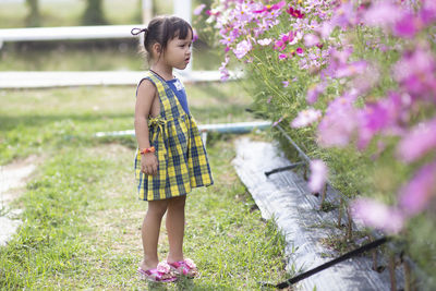 Side view of young woman standing against plants