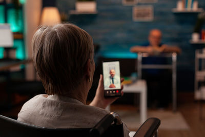 Rear view of man using mobile phone while sitting on table