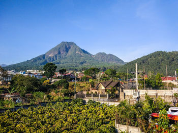 Scenic view of townscape and mountains against blue sky