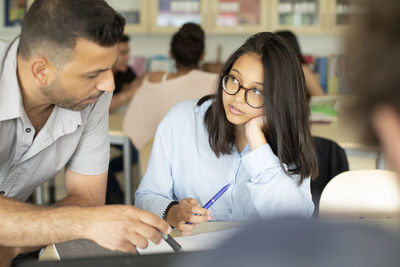 Male professor teaching teenager in classroom