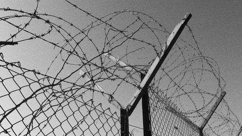 Low angle view of barbed wire fence against sky