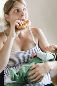 Woman eating food while carrying baby boy