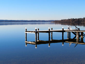 Pier on lake against clear blue sky