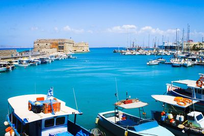 Boats moored at harbor against sky