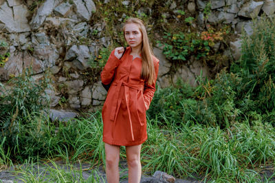 Portrait of young woman wearing orange dress on grassy field
