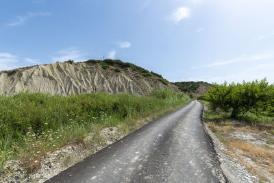 Road amidst land against sky