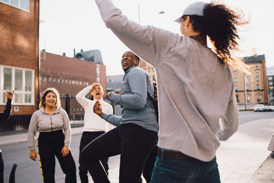 Multi-ethnic cheerful friends dancing on street in city