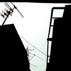 Low angle view of silhouette electricity pylon against clear sky