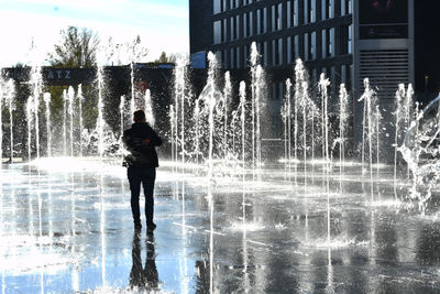 Rear view of man standing by fountain