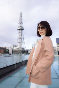 Woman standing by tower against sky