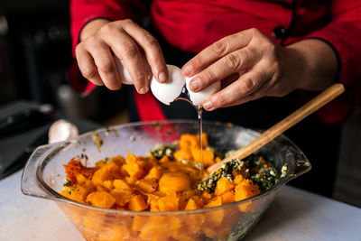 Stock photo of anonymous chef preparing meal in the kitchen and adding an egg.