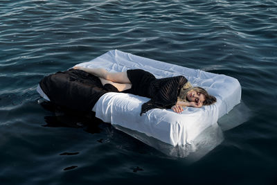 High angle view of woman sleeping on mattress in sea