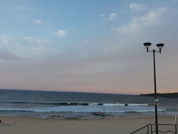 Street light on beach against sky during sunset