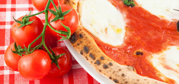 Close-up of cherry tomatoes by pizza on table