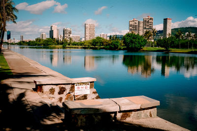 Buildings by lake against sky in city