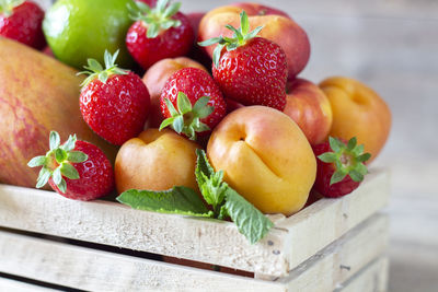 Fresh juicy fruits in basket on wooden background