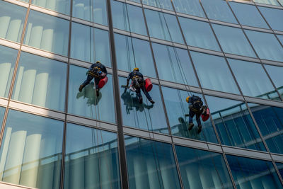 Milan italy march 29 2021 skilled glass cleaners who lower themselves with slings from above