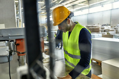 Worker operating drill in factory