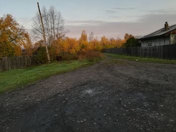 Road amidst trees and houses against sky during autumn