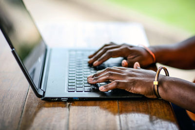 Close-up of man using laptop on table