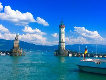 Lighthouse amidst sea and buildings against sky