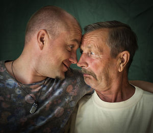 Close-up of gay couple face to face against curtain