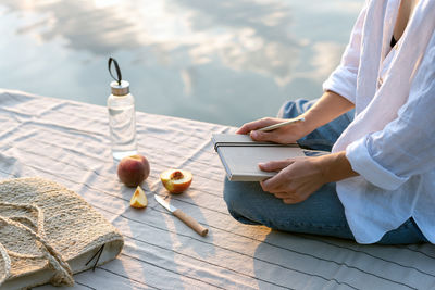 Summer picnic by the lake at sunset. woman relaxes in nature.