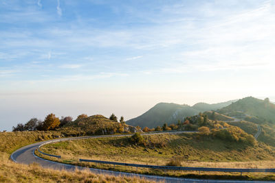 Road leading towards mountains against sky