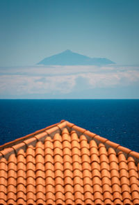 Building tile roof in a hill near ocean under blue clear sky