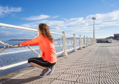 Rear view of woman walking on footpath against sky
