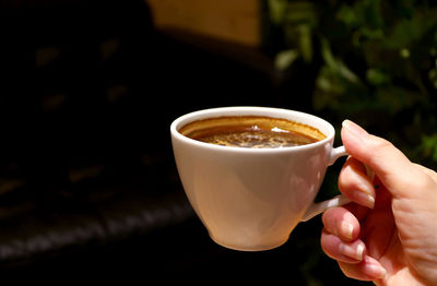 Closeup of woman's hand holding a cup of aromatic hot coffee