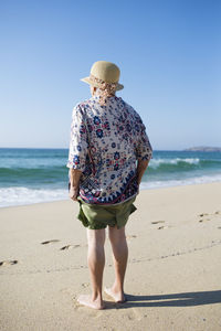 Back view of senior woman standing on the beach