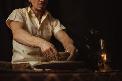 Man in pottery workshop makes plate of clay, an authentic atmosphere, yellow lamp, lifestyle,