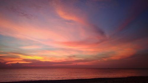 Scenic view of sea against dramatic sky during sunset