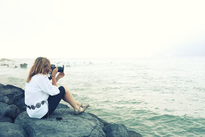 Full length of woman photographing on beach