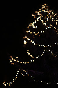 Low angle view of illuminated christmas tree against sky at night