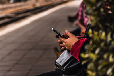 Midsection of man using mobile phone outdoors