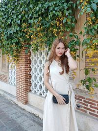 Portrait of young woman standing against plants