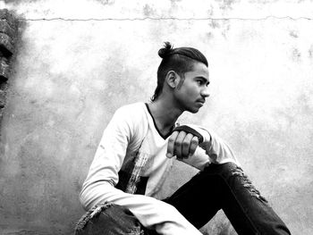 Young man sitting against wall